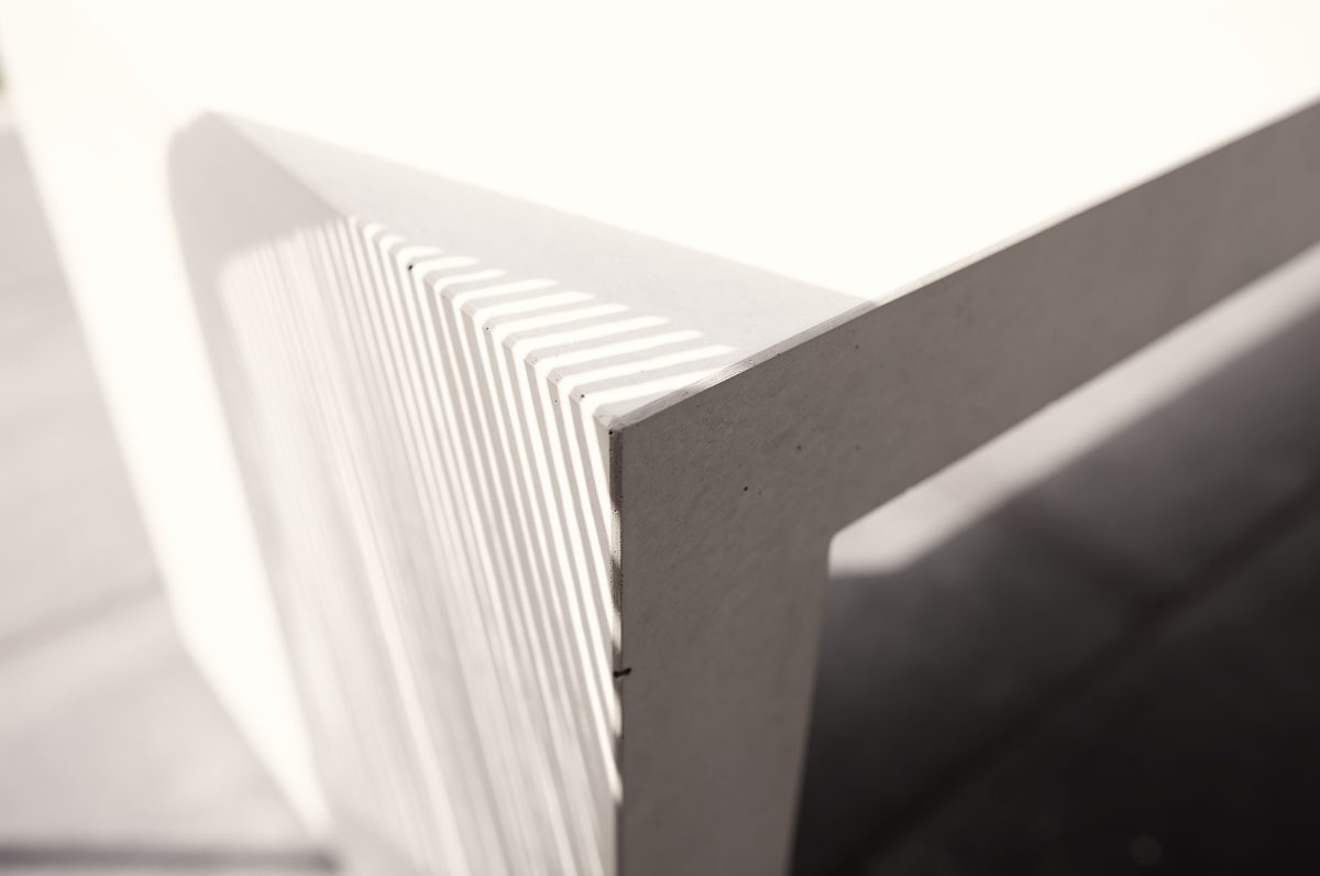 banco de hormigón arquitectónico que refleja la sombra de una silla de paja